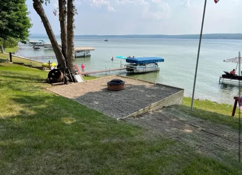 Lakeside view with a fire pit surrounded by grass and docks on the water.