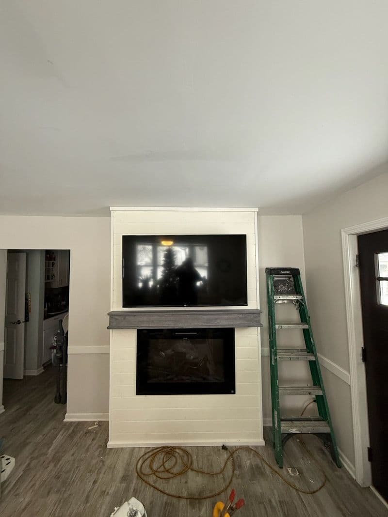 Modern living room featuring a wall-mounted TV above a fireplace with a ladder nearby.